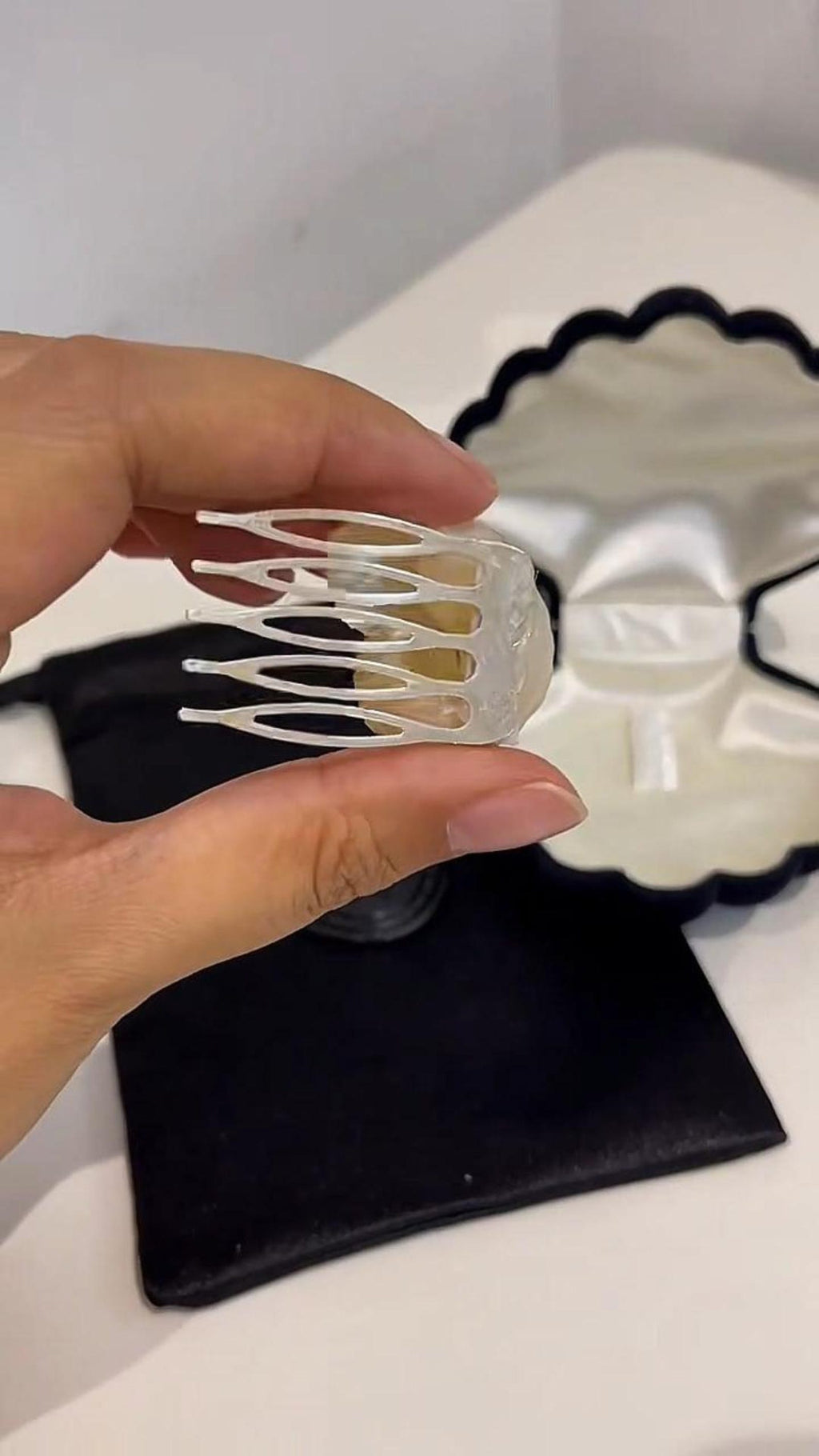 Back of a conch-shell hair comb held above its packaging.