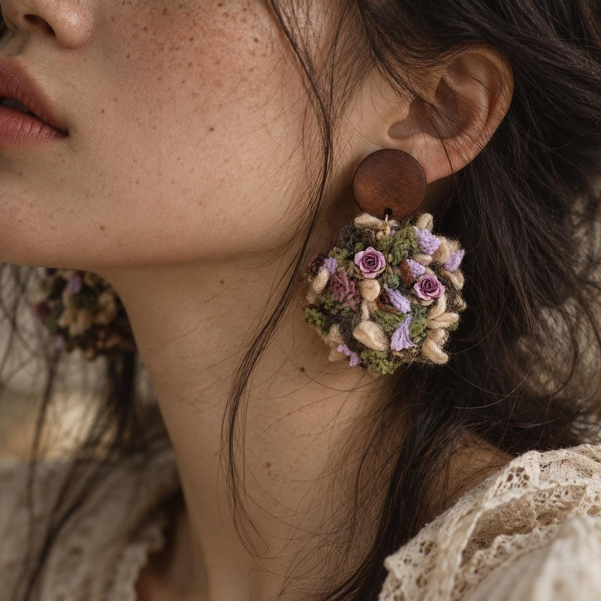 Yarn floral earring with a brown stud and small purple flowers, worn on an ear.