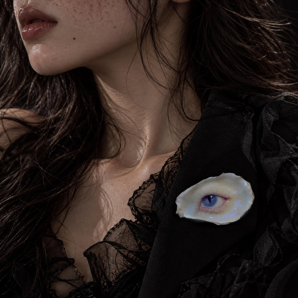 Nyx Cat blue-eye oyster shell brooch worn on black clothing.